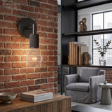 Black bare bulb sconce mounted on exposed brick in a loft room