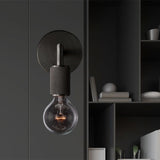 Black sconce on a dark gray wall beside open shelving