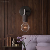 Black sconce on dark wood paneling beside a lilac sofa