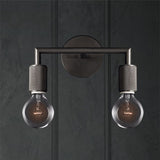 Two light black sconce on a dark paneled wall lit warm