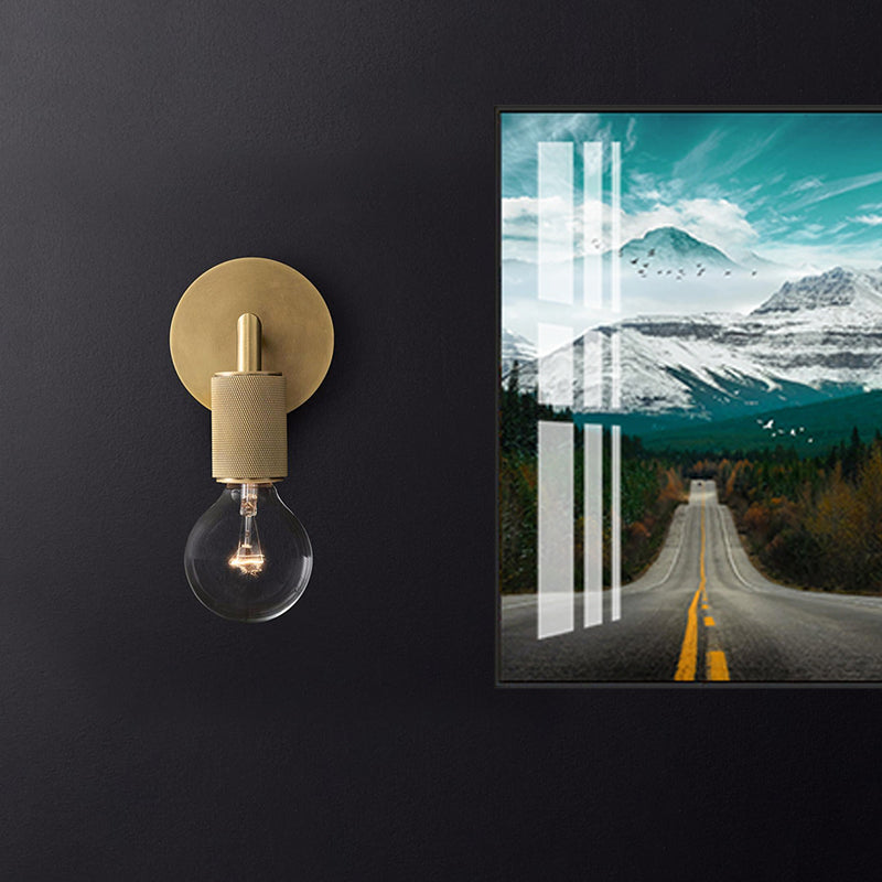 Brass sconce lit warm on a dark wall beside framed artwork