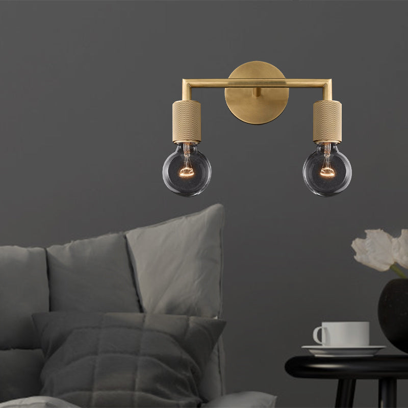 Two light brass sconce with bare bulbs above a bed on a gray wall