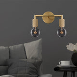 Two light brass sconce with bare bulbs above a bed on a gray wall