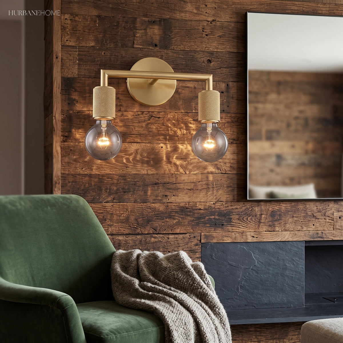 Two light brass sconce above a green armchair on reclaimed timber
