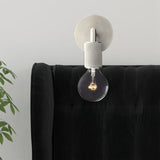 Chrome sconce lit above a black upholstered bed headboard