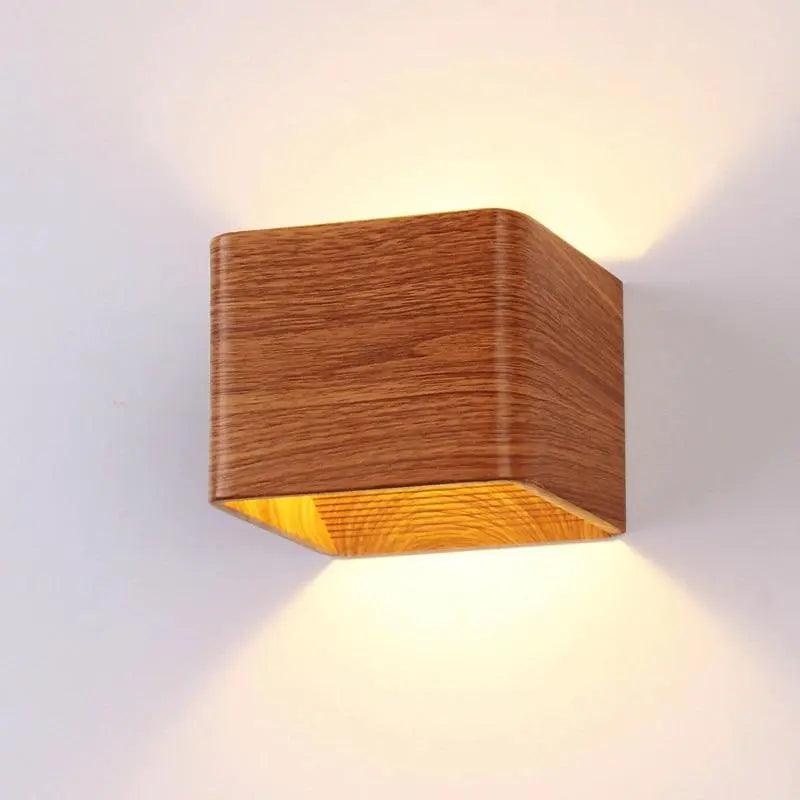 Wood cube wall sconce lit on a plain white wall from the side