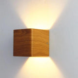 Wood cube wall sconce lit head on showing both cones of light