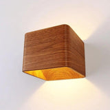 Wood cube wall sconce lit at an angle on a white wall