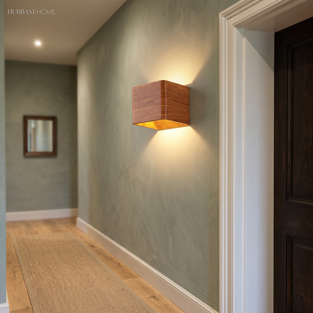 Wood cube wall sconce lit on a green hallway wall