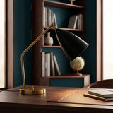 Black conical shade brass task lamp on a wooden desk