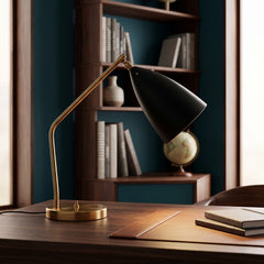 Black conical shade brass task lamp on a wooden desk