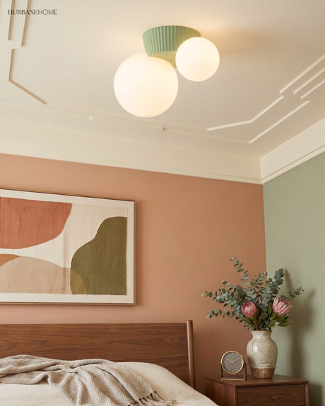Green canopy ceiling light with two opal globes above a made bed and artwork