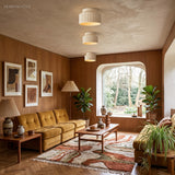 Pair of ribbed drum ceiling lights glowing in a walnut-panelled living room with mustard sofa