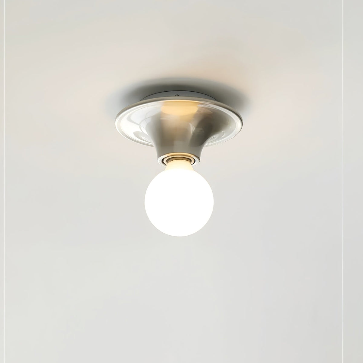 Nickel disc ceiling light mounted flush with the globe bulb facing down