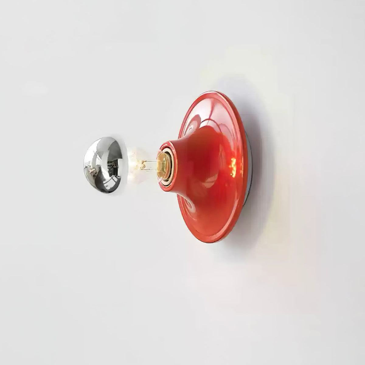 Red disc wall sconce with a mirror crown bulb on a white wall