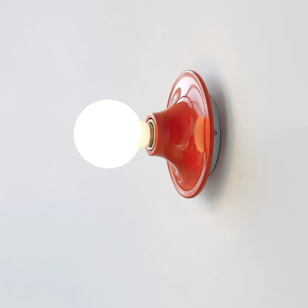 Red disc wall sconce with a bright opal globe bulb on white