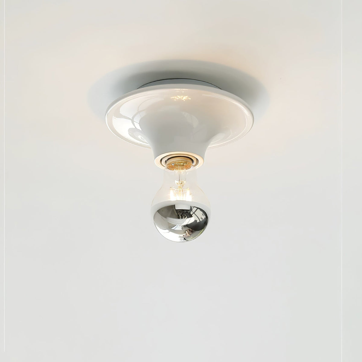 White disc ceiling light mounted flush with a mirror crown bulb below