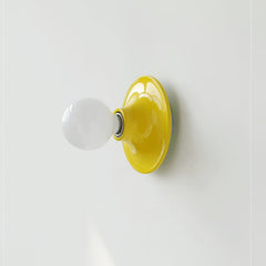 Yellow disc wall sconce seen from an angle with an opal globe bulb