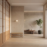 Globe wall sconce lit in a pale hallway beside slatted screens and a bench