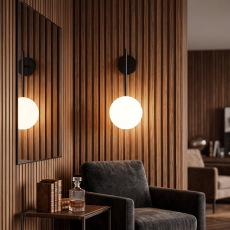 Two black globe sconces lit on a slatted timber wall beside a leather armchair