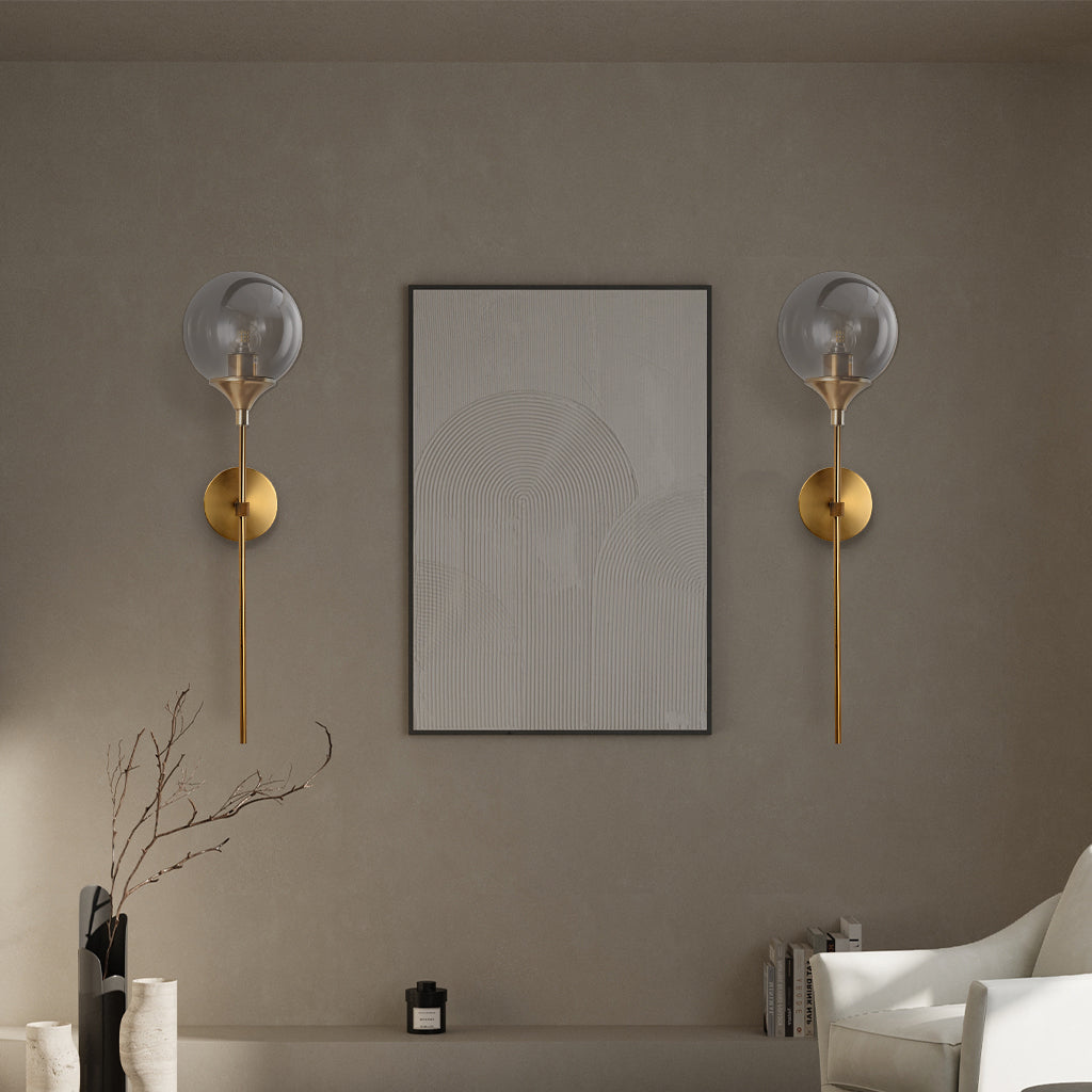 Modern glass globe wall sconce angled view on a brass stem