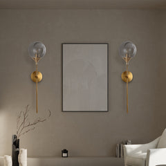 Modern glass globe wall sconce angled view on a brass stem