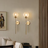 Modern glass globe wall sconce studio view on a brass stem