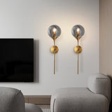 Modern glass globe wall sconce studio angle on a brass stem