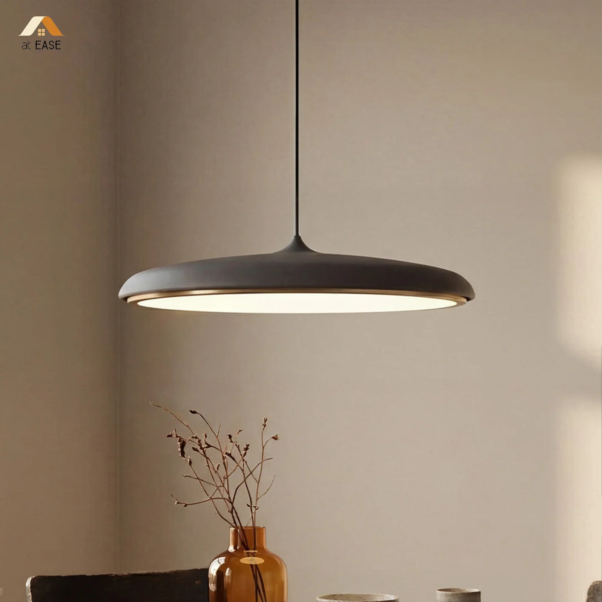 Black disc pendant light lit from below highlighting the frosted diffuser