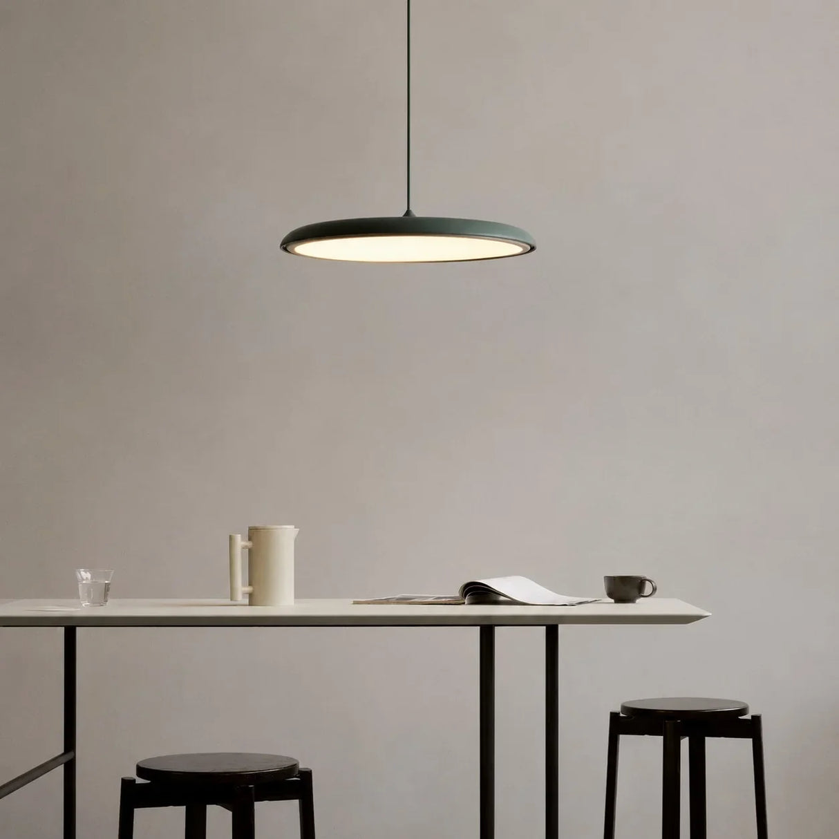 Green disc pendant light with a slim metal shade over a light interior