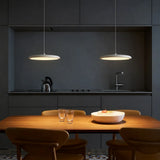 Orange disc pendant light hanging in a bright modern room