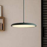 Pink disc pendant light hanging low over a neutral toned interior