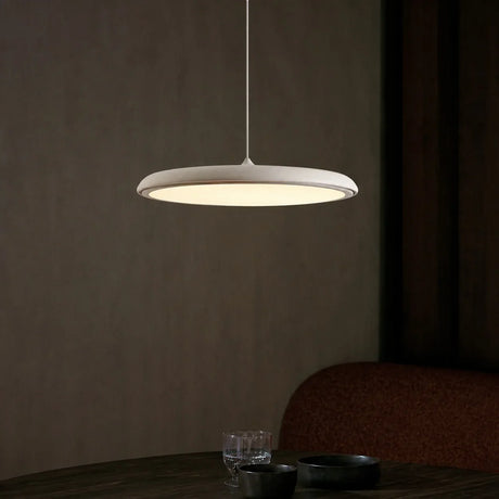 White disc pendant light shown from a raised angle against a plain backdrop