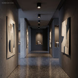 Surface mount spotlights washing artwork on dark blue gallery hallway walls