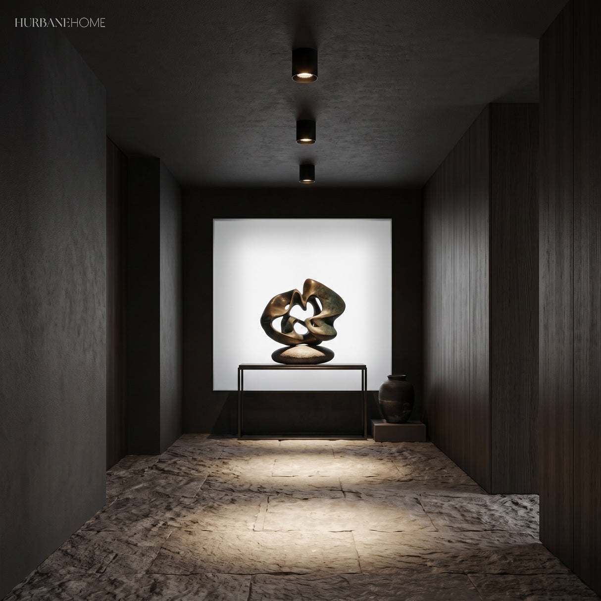 Black surface mount spotlights lighting a bronze sculpture in dark hallway