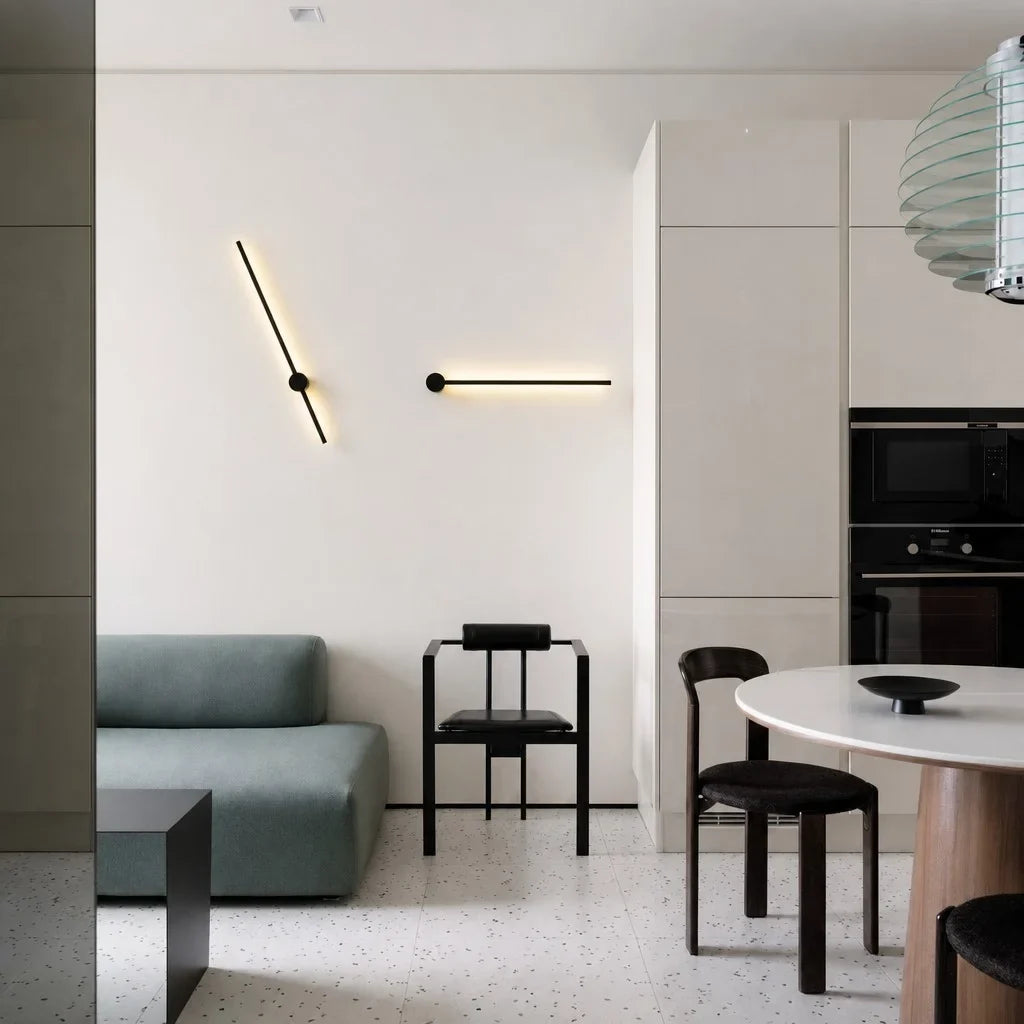 Two angled black wall sconces in a beige open-plan kitchen and living area