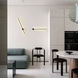 Two angled black wall sconces in a beige open-plan kitchen and living area