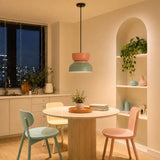 Pink and light green pendant lit in a beige kitchen-diner at night