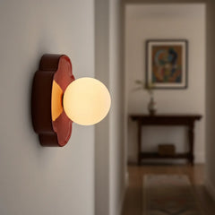 Beige orb wall sconce three-quarter view with rounded flower backplate