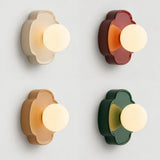 Green flower-shaped orb wall sconce with frosted glass globe on white