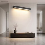 Wide linear sconce washing light down a pale interior hallway wall