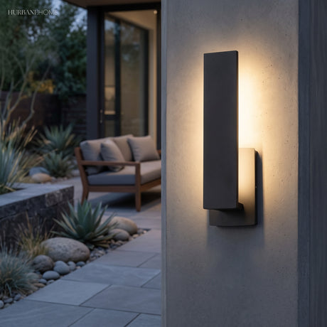 Tall black rectangular sconce lit on a dark stone exterior wall