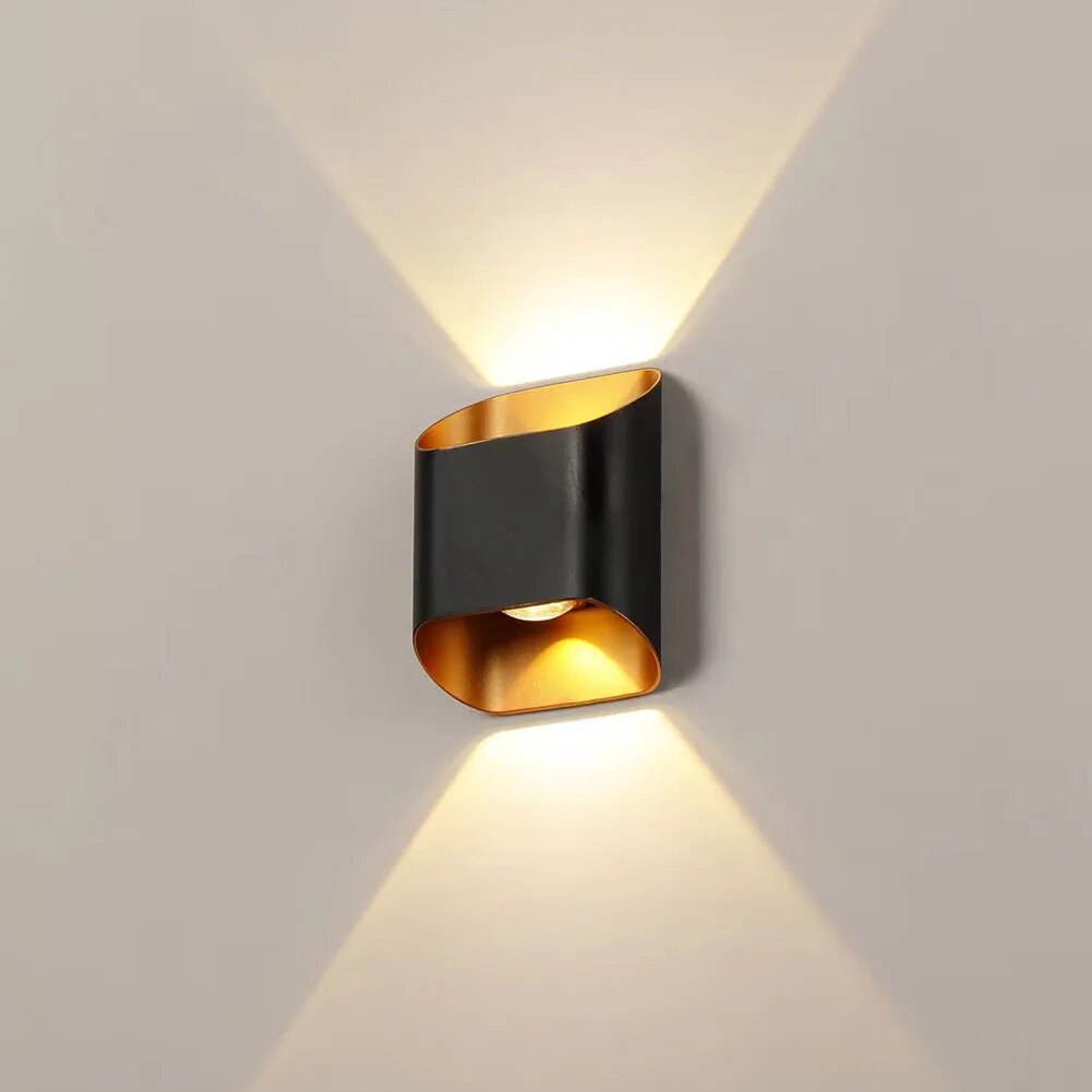 Black up down wall sconce lit on a pale wall showing two beams