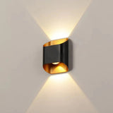 Black up down wall sconce lit on a pale wall showing two beams
