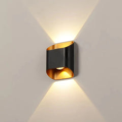 Black up down wall sconce lit on a pale wall showing two beams