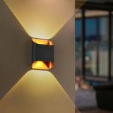 Black up down sconce lit on a wall beside a glass corner window