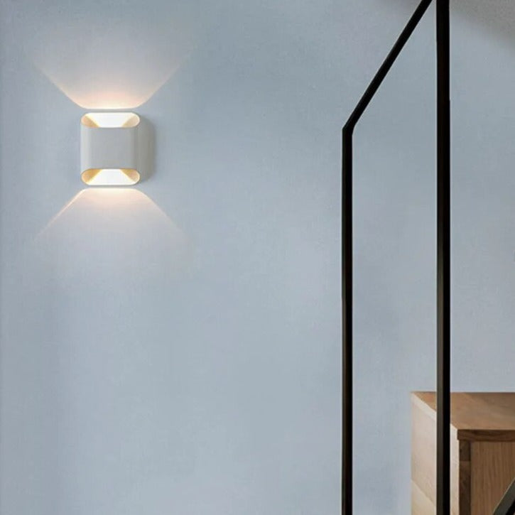 White up down sconce lit on a wall beside a black framed door