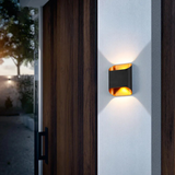 Black up down sconce lit on a wall beside a timber front door