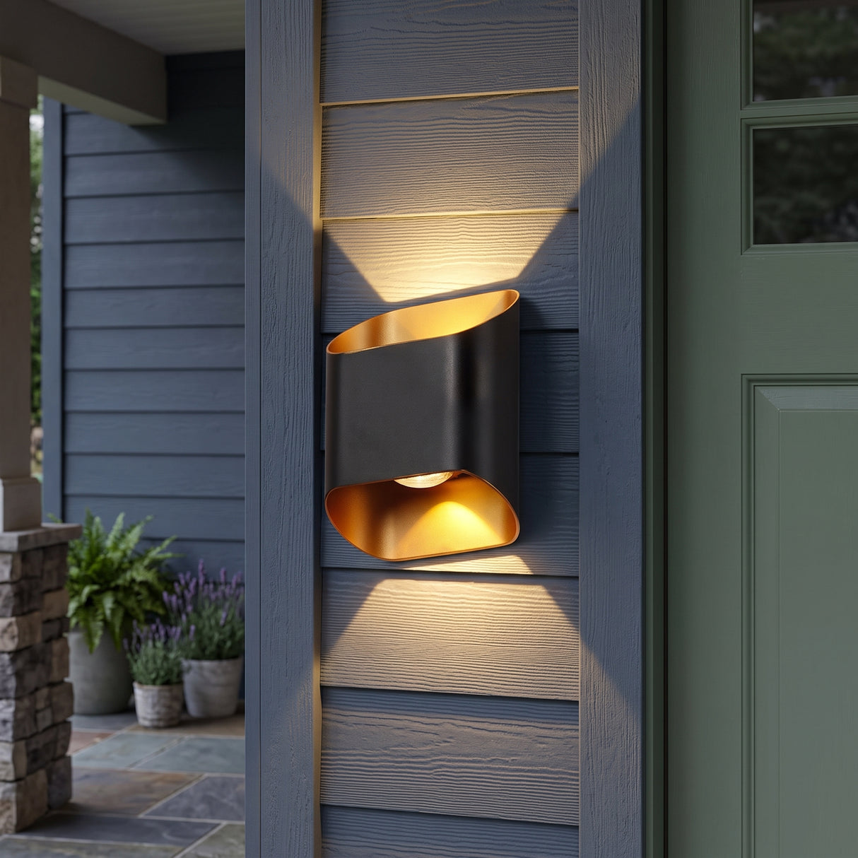 Black up and down outdoor wall sconce lit beside a green front door
