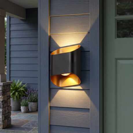 Black up and down outdoor wall sconce lit beside a green front door